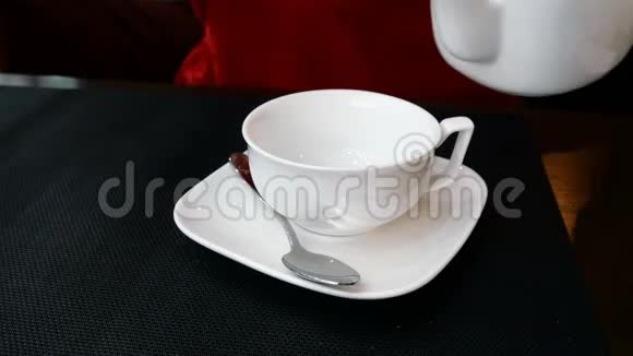 热鲜茶从白色陶瓷茶壶中倒入白色杯子视频的预览图