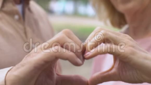 成熟的男人和女人用手指显示出心脏的迹象甜蜜的爱亲密的视频的预览图