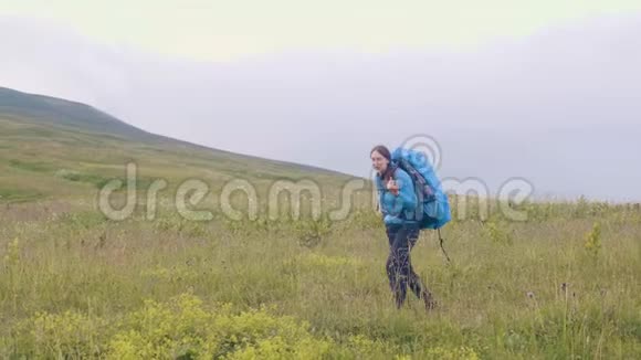 带背包的旅行妇女在青山上漫步视频的预览图