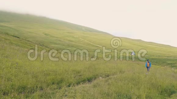 旅游妇女漫步在青山绿水的草地上视频的预览图