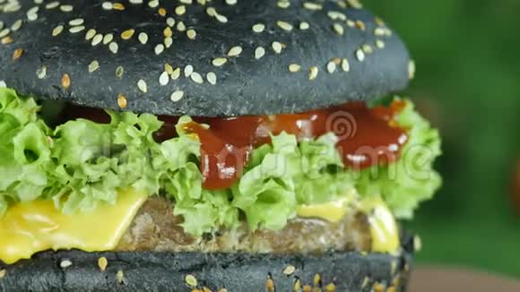 在绿色和蔬菜的模糊背景上用黑色面包和芝麻做汉堡或汉堡视频的预览图