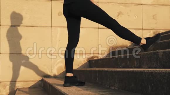 穿着黑色运动服的年轻女子在训练中弯曲大腿内侧的肌肉女孩伸展腿部肌肉视频的预览图