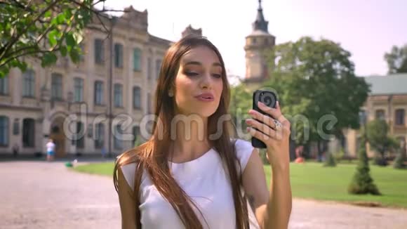 漂亮的年轻女人白天站在公园里在电视上聊天交流的概念视频的预览图