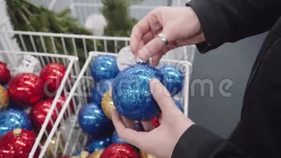 女人选择圣诞玩具手里拿着蓝色和金色的球视频的预览图