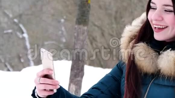 冬雪森林中使用智能手机自拍的年轻女性视频的预览图