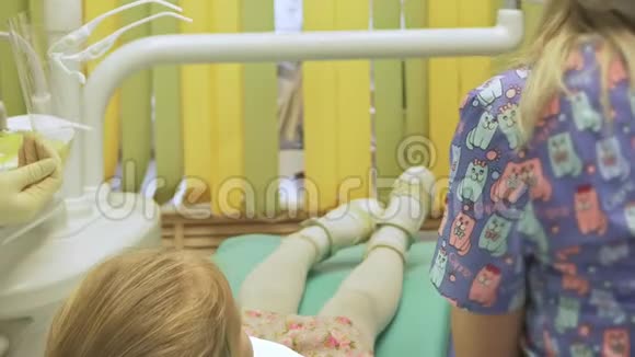 带着一个母亲的孩子在牙医接待处女孩躺在椅子上在她母亲的身后医生和一个视频的预览图
