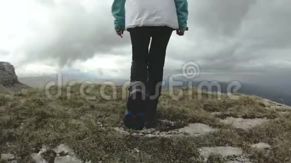这个女孩在一个高耸的悬崖旁的高原上行走旅游理念视频的预览图