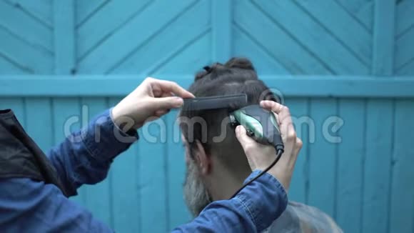 在露天理发店男士们用电动剃须刀剪头剪头发型视频的预览图