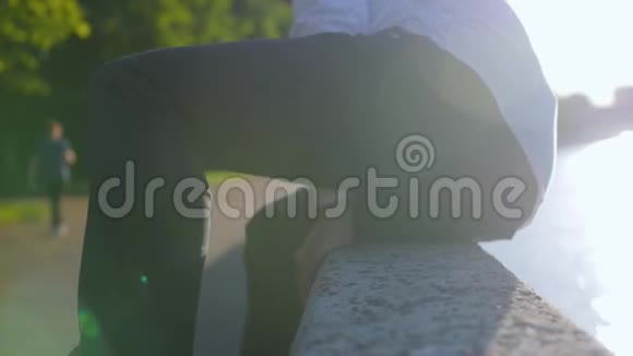 男人穿着经典的衬衫坐在公园的石栅栏上近距离射击视频的预览图