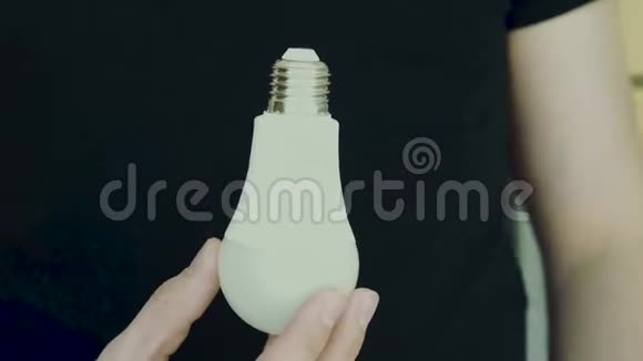 一个人手里拿着一盏灯手里拿着一个灯泡放在黑色的背景上视频的预览图