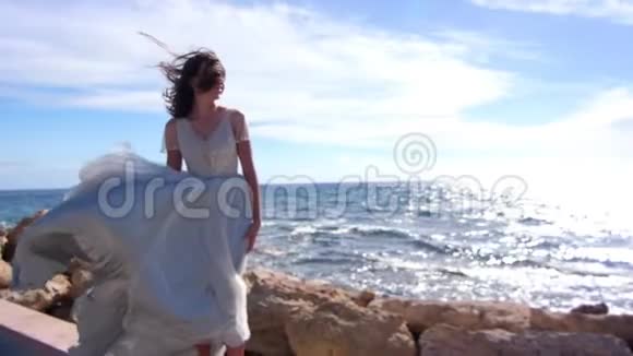 优雅的女人在岩石海岸跳跃性感少女欣赏海景视频的预览图