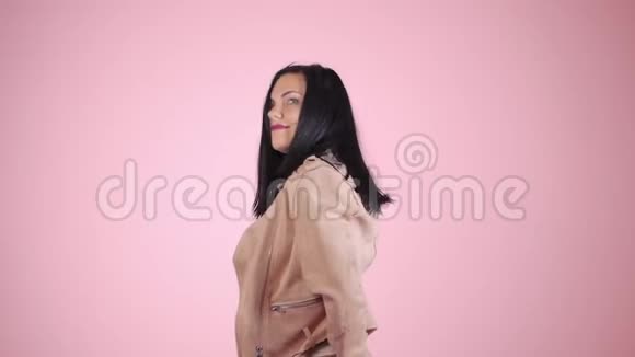 穿着粉色夹克跳舞的漂亮姑娘有深色头发的时装模特在工作室里移动身体视频的预览图