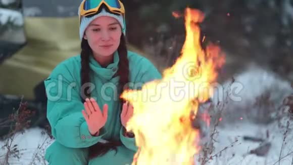冬季森林一位年轻女子坐在篝火旁取暖视频的预览图