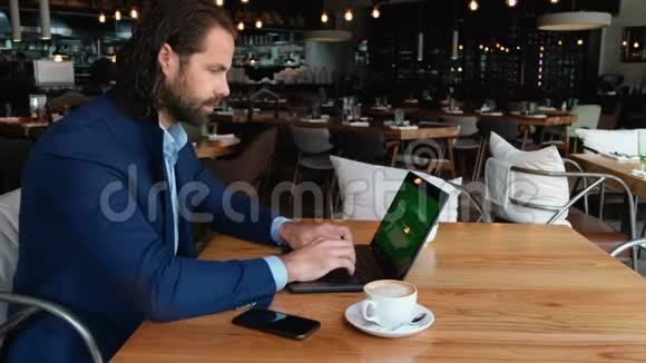 年轻的欧洲商人坐在咖啡馆里的一张桌子旁在咖啡休息时用笔记本电脑打字视频的预览图