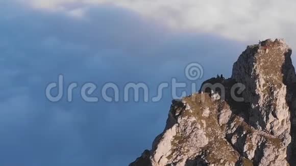 高空飞行的登山者在高高的云层之上的山顶上视频的预览图