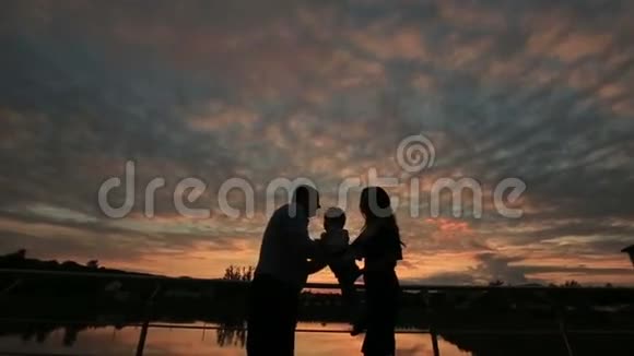 日落时分幸福的家庭在一起散步的剪影视频的预览图
