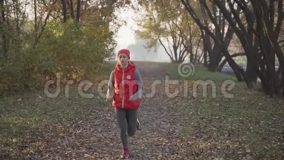 早晨在浓雾中在城市公园慢跑一位年轻女子日出任何天气概念下的健康生活方式视频的预览图