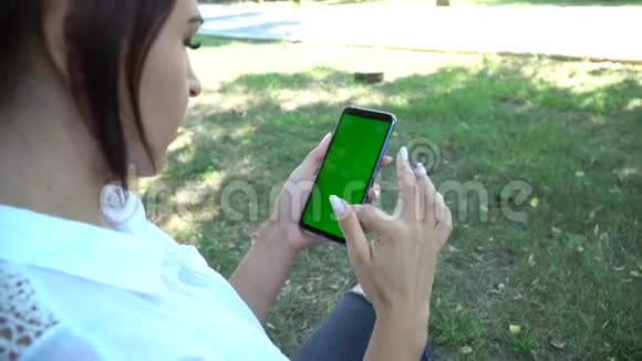 女子手持智能手机绿色屏幕特写色度视频的预览图