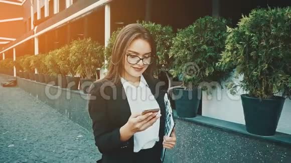 年轻漂亮聪明的商务女孩穿着商务服走路在这段时间里她拿着一个文件夹视频的预览图