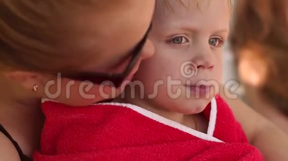 妈妈抱着裹着毛巾的儿子在游泳池旁视频的预览图