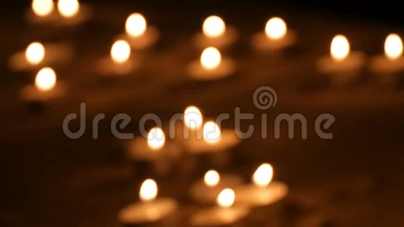 许多美丽的模糊圆形白色的小蜡烛在黑暗的沙子里燃烧视频的预览图
