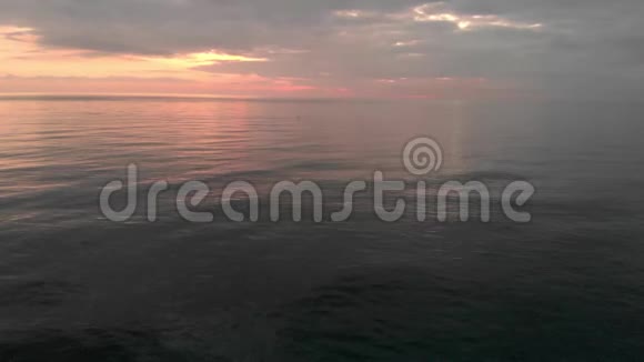 美丽多云的日落在海上运动员在远处练习直立划桨视频的预览图