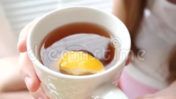 女孩喝着热茶一片柠檬坐在窗台上微笑着视频的预览图