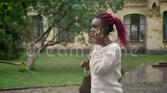 年轻漂亮的女学生离开大学正在打电话一个带着粉色长发的女人走进来视频的预览图