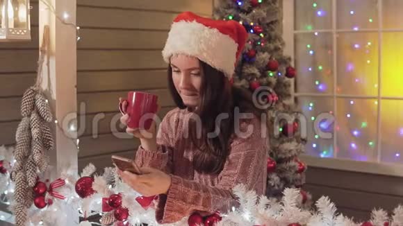 戴着圣诞帽的布鲁内特女士发短信和圣诞祝福视频的预览图