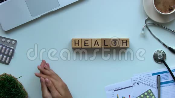 健康单词桌子上的木立方体医生拿着玩具心脏捐献者视频的预览图