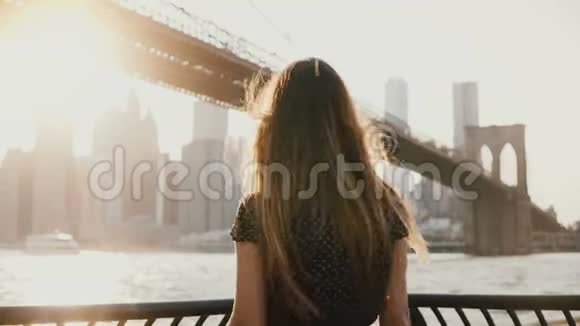 后景的快乐旅游女孩与飞毛欣赏布鲁克林大桥在纽约从路堤手臂开放视频的预览图