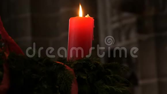 一支巨大的蜡红色蜡烛在天花板下燃烧站在一个天主教教堂的冷杉花环里视频的预览图