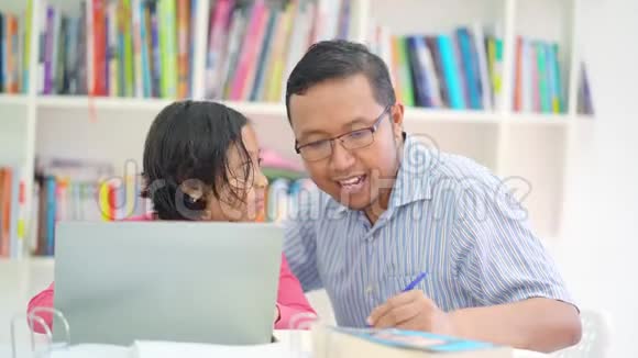 小女孩用笔记本电脑学习她的父亲视频的预览图