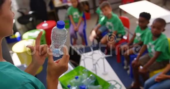 白人女教师在教室里教小孩瓶子回收视频的预览图