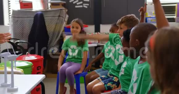 混合种族学童在教室里举手的侧视视频的预览图
