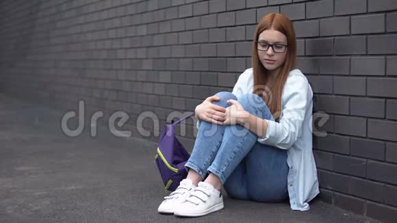 孤独女学生眼镜坐在高中后院的地板上问题视频的预览图
