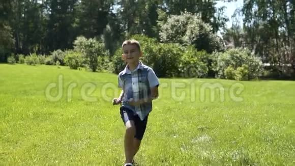 一个有魅力的男孩在阳光明媚的天气里沿着公园的草地跑步心情很好慢动作视频的预览图