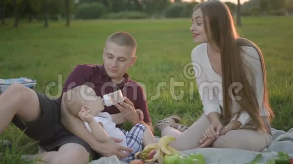 小男孩在野餐时从瓶子里喝水妈妈和他一起玩视频的预览图
