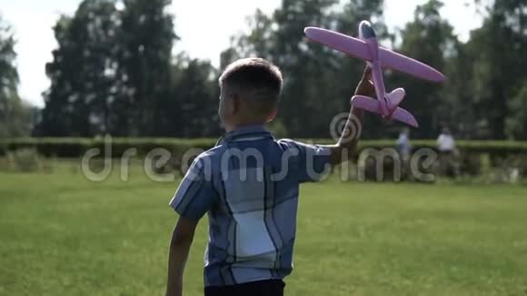 男孩在阳光明媚的天气在公园里开了一架玩具飞机慢动作视频的预览图
