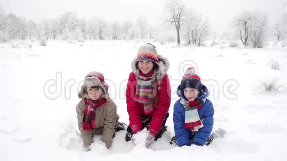 三个快乐的孩子在冬天的风景上撒雪慢动作视频的预览图