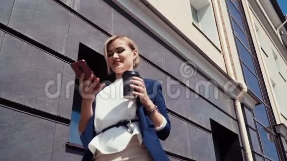 商人站在办公楼附近后面有窗户1金发女郎穿着一件浅色上衣视频的预览图