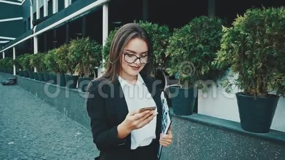 年轻漂亮聪明的商务女孩穿着商务服走路在这段时间里她拿着一个文件夹视频的预览图