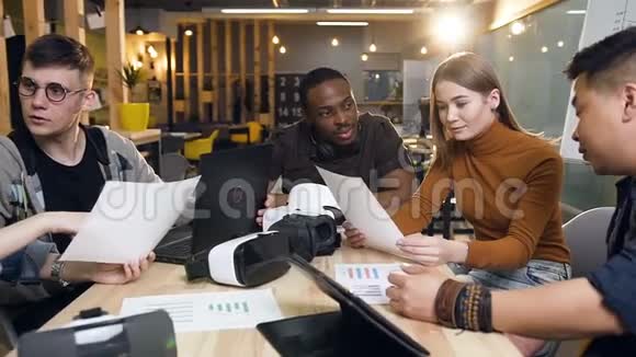 一群年轻的商人一边拿着文件一边坐在桌子旁视频的预览图