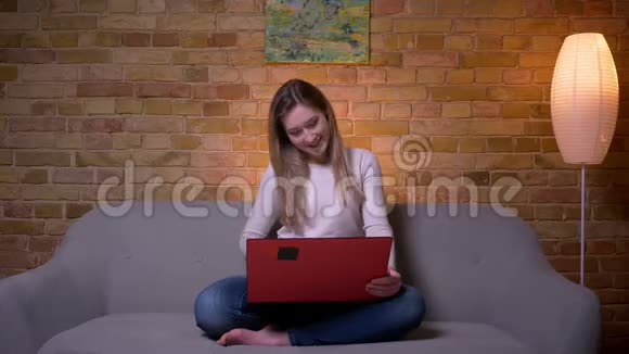 年轻迷人的白种人深色头发的女性特写镜头她在笔记本电脑上看一部有趣的电影笑着视频的预览图