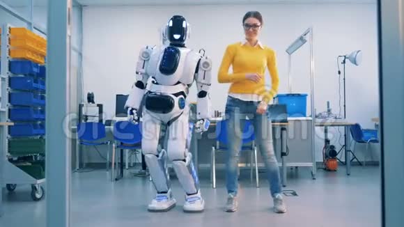 年轻的女人和一个机器人跳舞机器人在她离开后玩得很开心视频的预览图