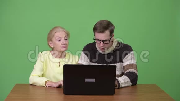 高级女商人和年轻的帅哥一起用笔记本电脑和恐慌视频的预览图