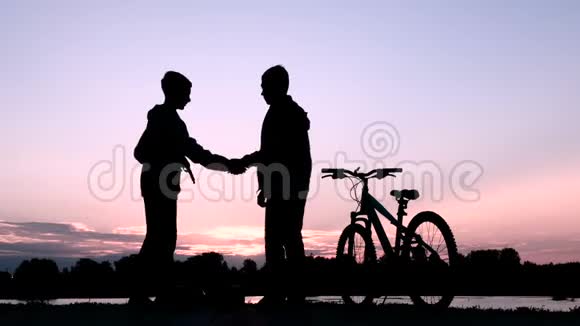 两个年轻人握手道别一个少年骑着自行车离开另一个人骑着两辆视频的预览图