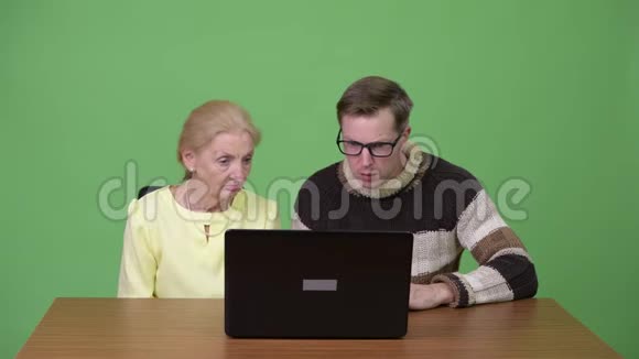 高级女商人和年轻的帅哥一起使用笔记本电脑视频的预览图