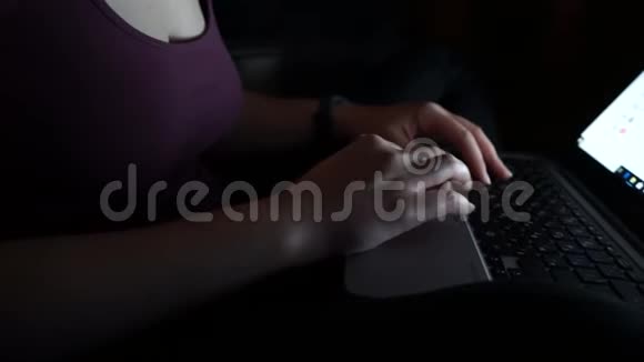 女人在黑暗的夜晚用笔记本电脑打字手在关键字与电脑上面打字晚期网瘾或工作视频的预览图