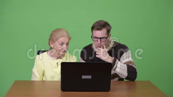 高级女商人和年轻的帅哥一起使用笔记本电脑视频的预览图